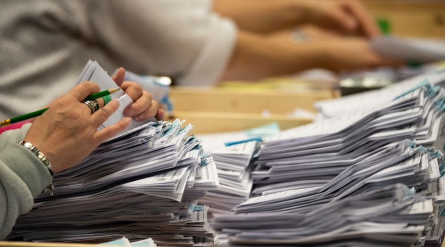 Image of someone counting paper voting ballots